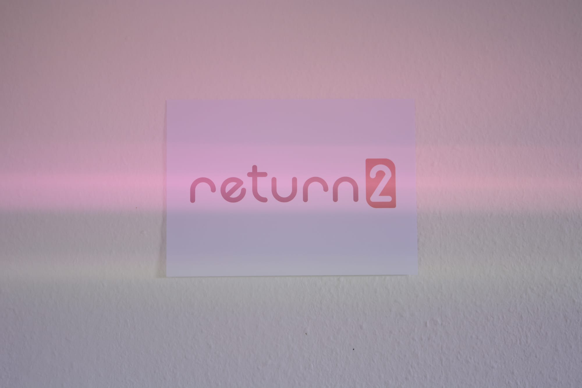 A picture of the return2 logo with a pink horizontal line